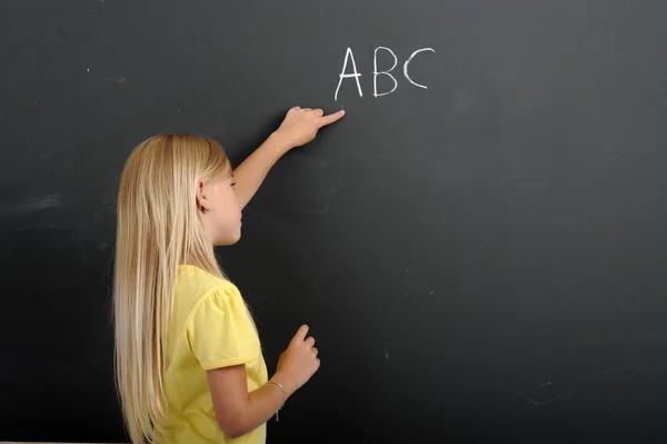Mädchen schreibt Abc auf eine Tafel — Stockfoto
