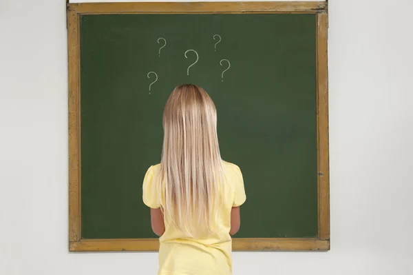 Flickan står framför svarta tavlan i ett klassrum — Stockfoto