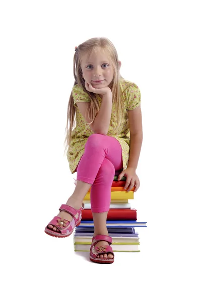 Kleines Mädchen sitzt auf einem Stapel Bücher — Stockfoto