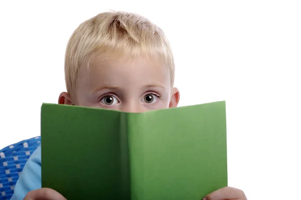 Little boy with big eyes looking from over a book — Stock Photo, Image