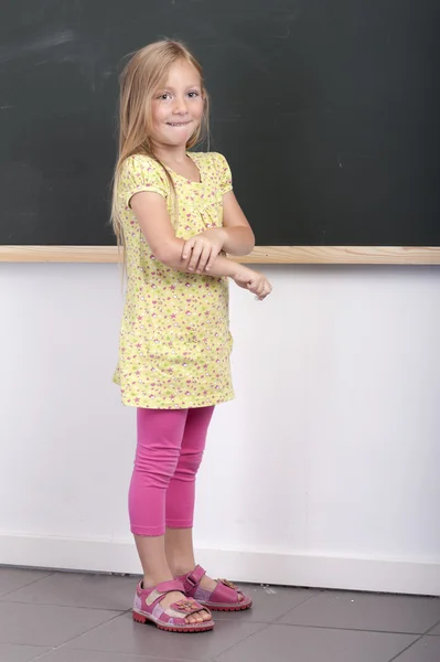 Girl standing in front of an old chalkboard — Stock Photo, Image