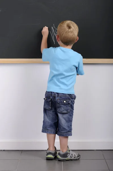 Liten pojke skriva på en svart tavla — Stockfoto