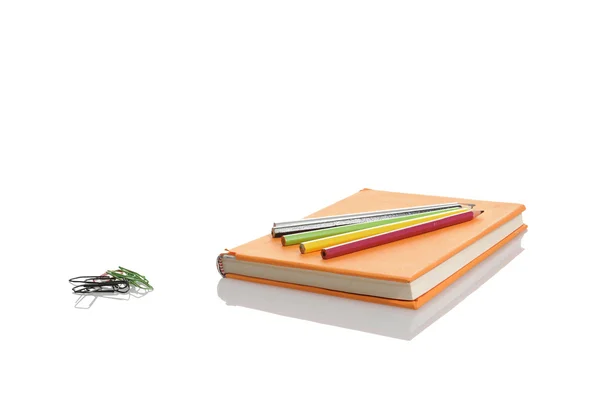 Orange bok och pennor på vit — Stockfoto