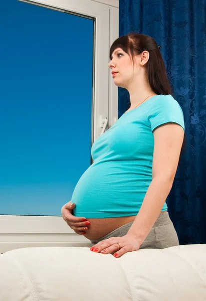 Беременная женщина у окна — стоковое фото