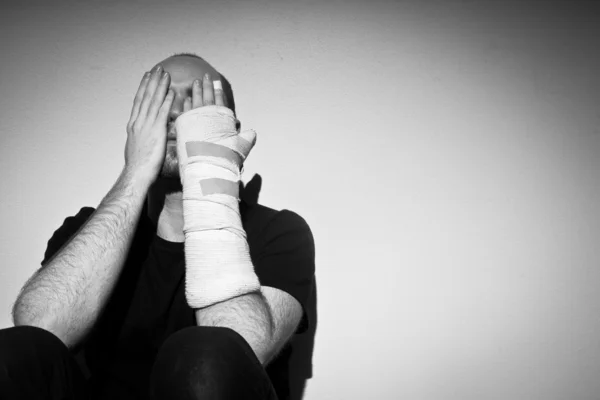 Przygnębiony człowiek dorosły ręką rannych — Zdjęcie stockowe