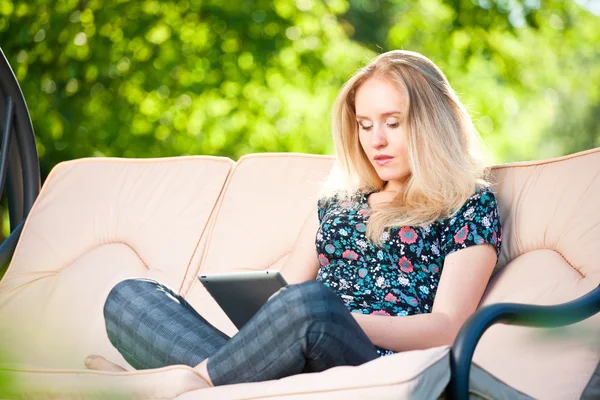 Positive beautiful young woman sitting outdoors in armchair seat — Stock Photo, Image