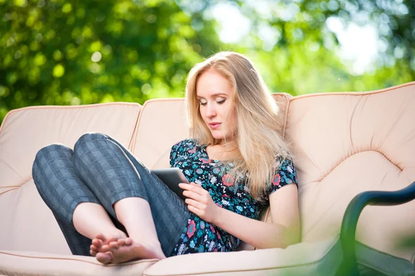 Positiva vacker ung kvinna sitter utomhus i fåtölj stol — Stockfoto