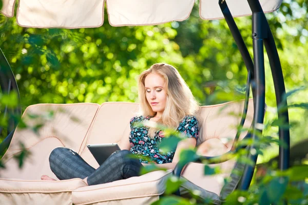 Positiva hermosa mujer joven sentada al aire libre en sillón asiento Imágenes de stock libres de derechos