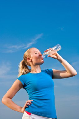 Young female athlete drinkig water to refresh during a hot weath clipart