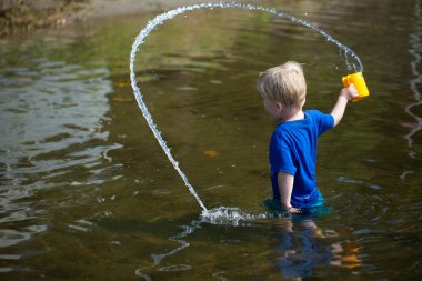 Boy tosses water from cup in lake clipart