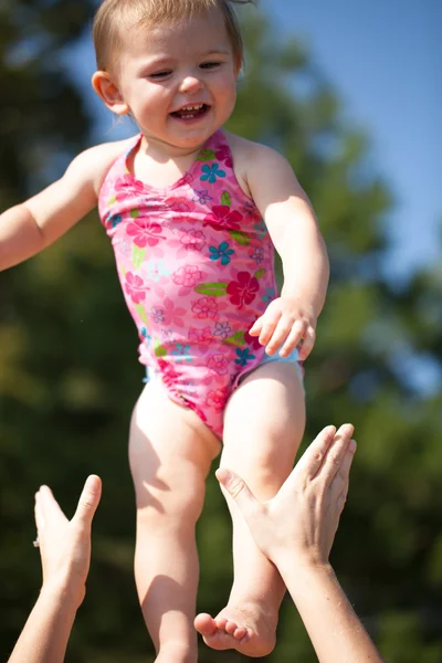 Baby being tossed in air while smiling — Stock Photo, Image
