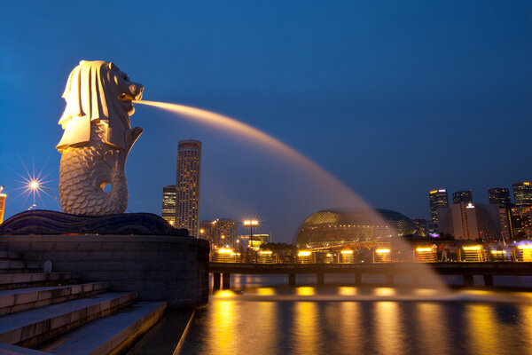 Merlion fountain spouts water of the Singapore skyline in night.