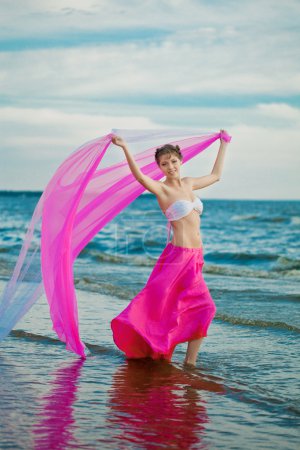 Femme avec un mouchoir dans les mains sur la plage 