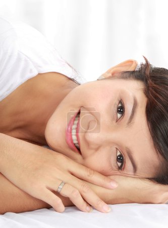 Femme souriante tout en étant couchée sur le lit 